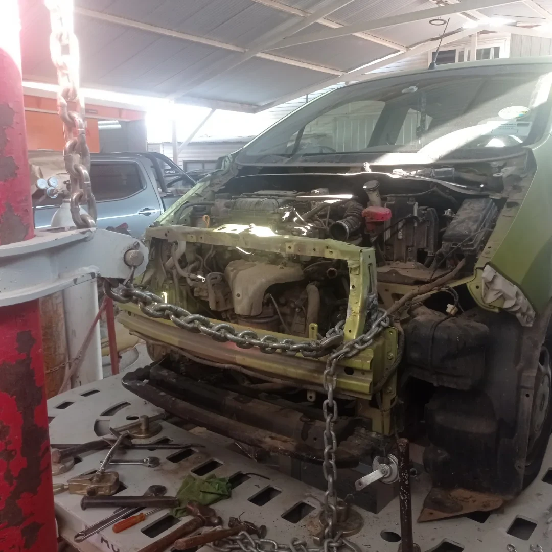 Chevrolet Spark verde en mesa de estirado durante la reparación
